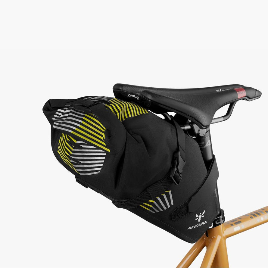 Sacoche de selle bikepacking Apidura Racing noire avec motifs jaunes, robuste et légère pour aventures vélo longues distances