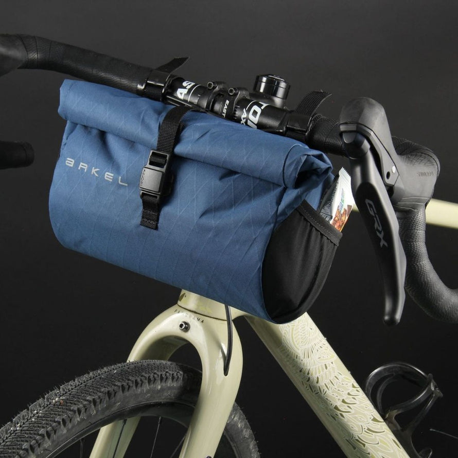 Sacoche de guidon etanche Arkel Burrito bleu fixee sur un velo gravel avec fermeture par boucle securisee