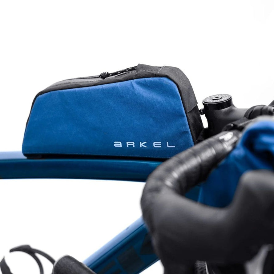 Sacoche top tube Arkel Taco bleue sur cadre de vélo, idéale pour transporter accessoires et outils en bikepacking