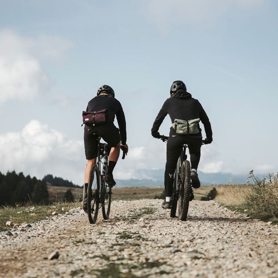 Deux cyclistes gravel roulant avec une banane MeroMero Piha fixée à la taille