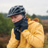 Cycliste ajustant le masque facial Vaude Warm sous un casque vélo pour se protéger du froid.