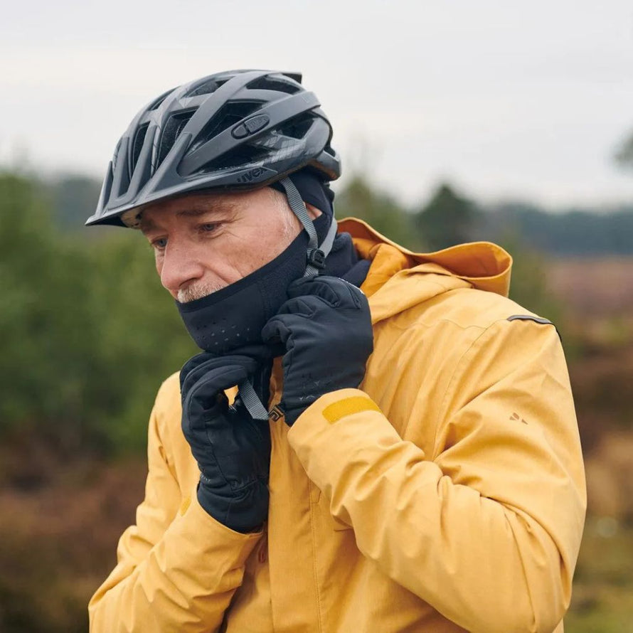 Cycliste ajustant le masque facial Vaude Warm sous un casque vélo pour se protéger du froid.