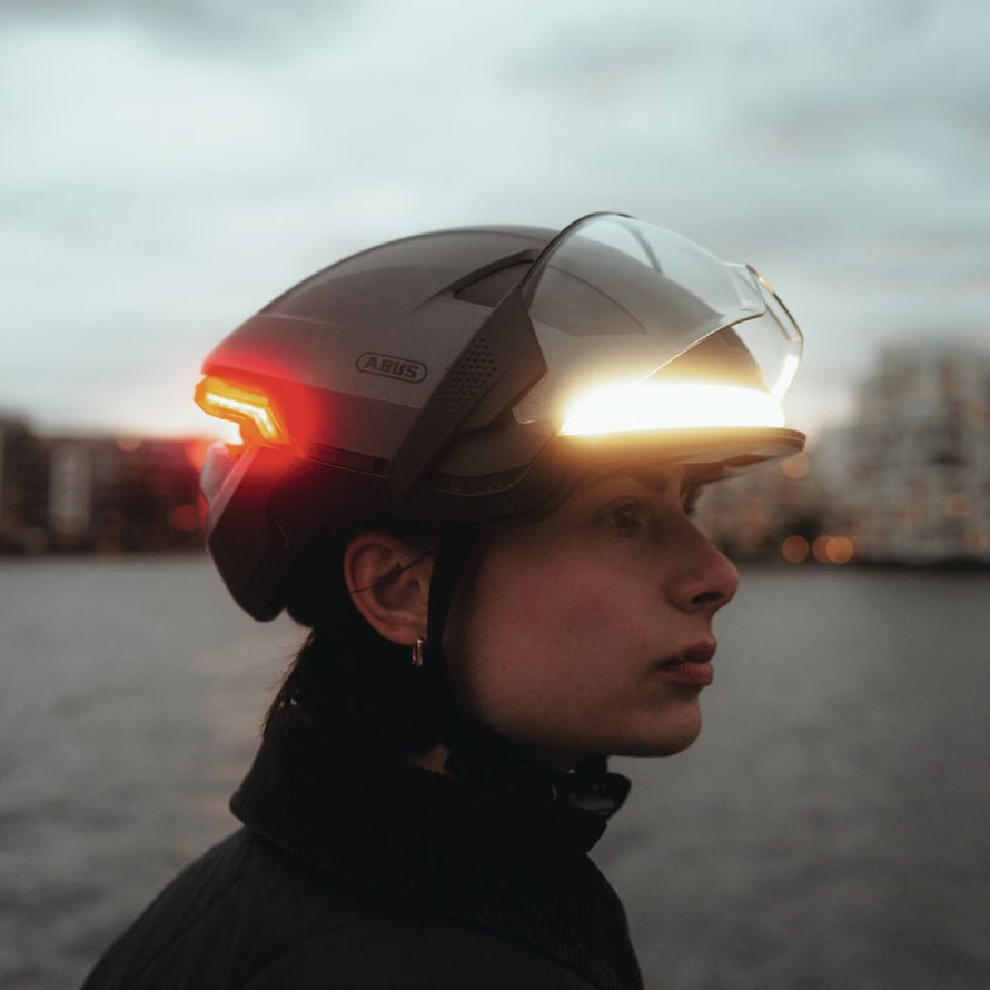 Casque vélo Abus Hyp-E Ace porté de profil avec visière relevable et double éclairage led avant et arrière pour rouler de nuit