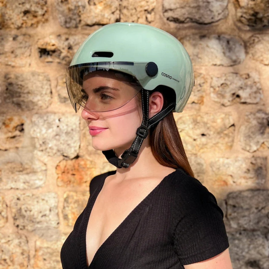 casque velo connecté cosmo fusion vert avec visière intégrée porté par une femme en extérieur