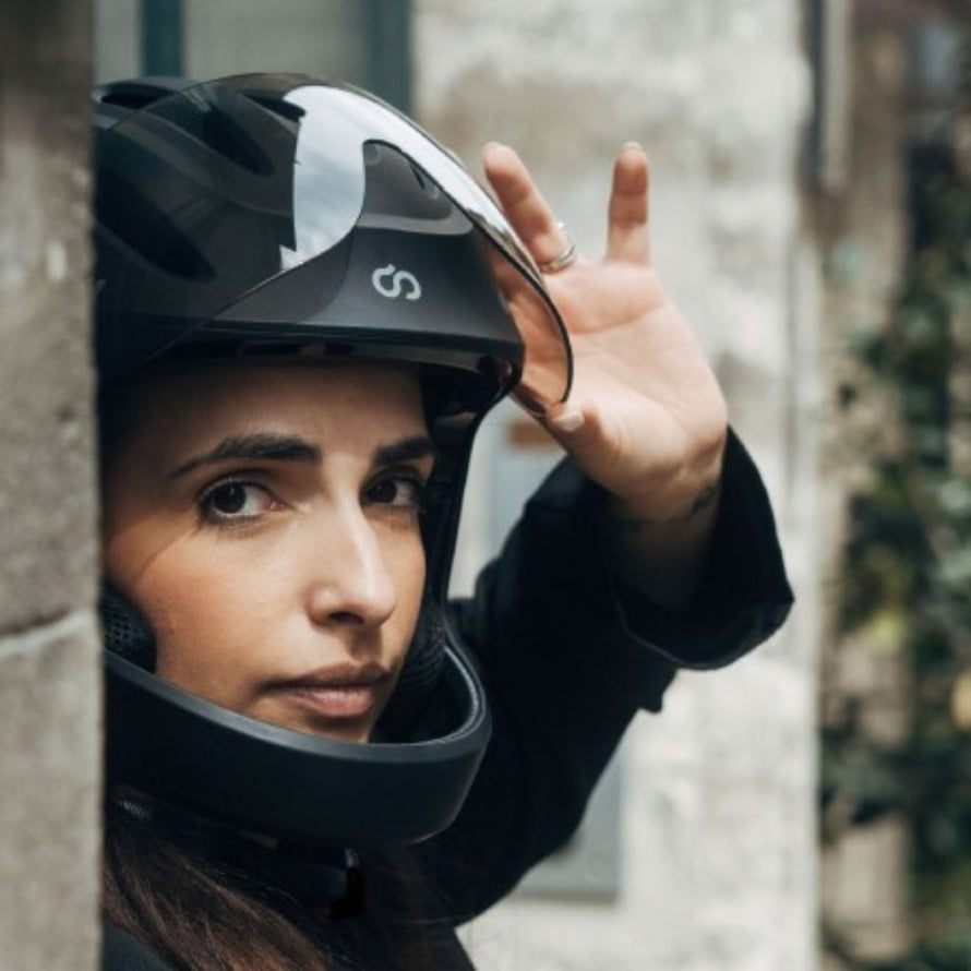 Femme en déplacement urbain portant le casque de vélo électrique intégral Virgo Integral noir avec visière protectrice.