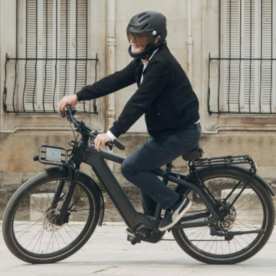 Homme roulant en ville sur un vélo électrique équipé du casque intégral Virgo Integral noir, conçu pour la sécurité quotidienne.