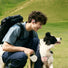 Jeune homme avec ecouteurs velo Shokz OpenFit Air 2 profite d'une balade en plein air avec son chien