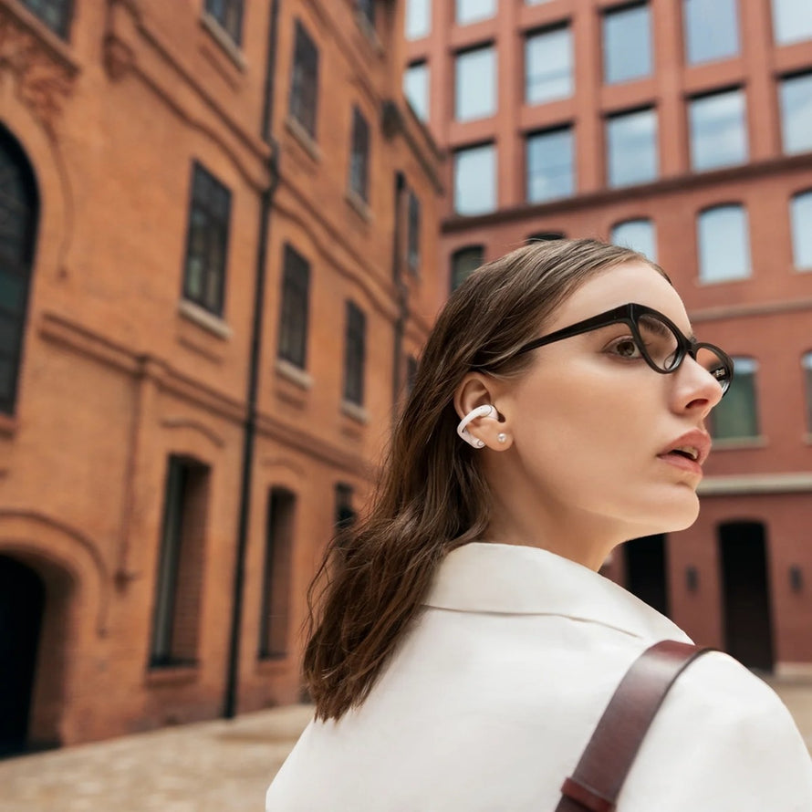 Femme en ville portant ecouteurs bluetooth velo Shokz Opendots 2 pour une experience audio claire et sans fil
