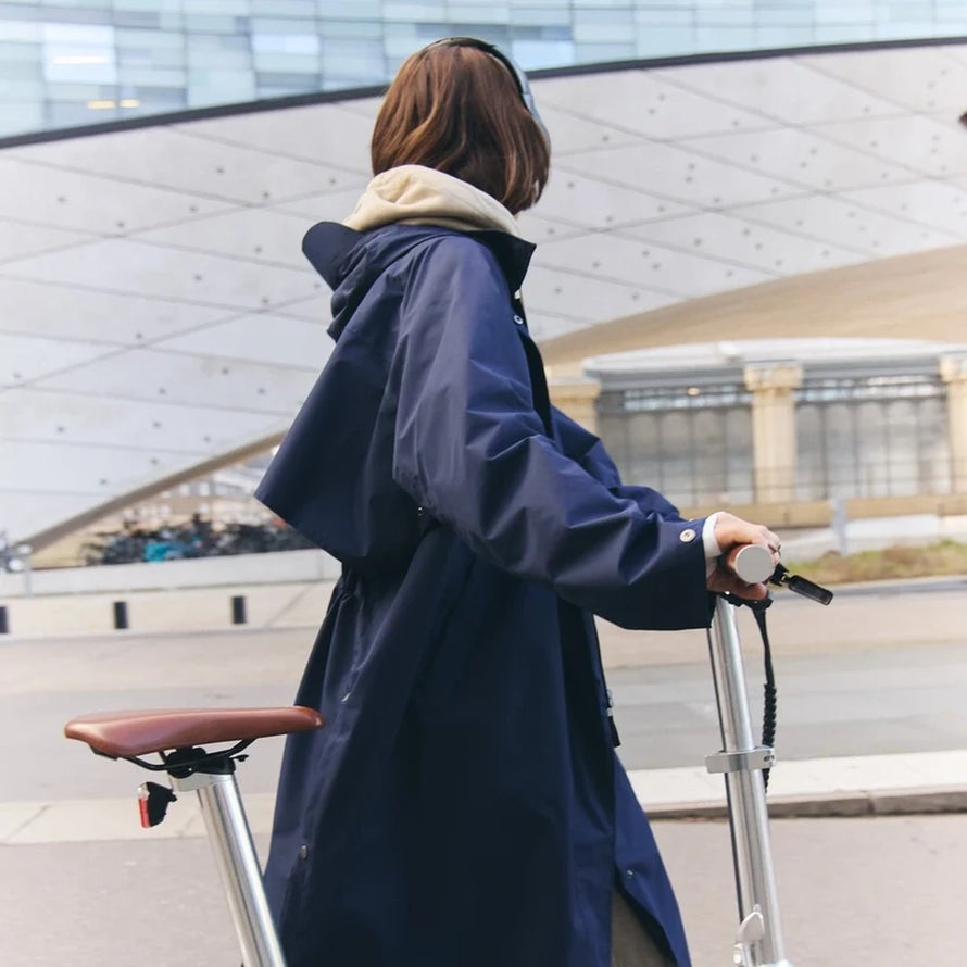 Trench-coat imperméable unisexe Fudoon bleu marine porté en ville avec trottinette, style urbain et protection pluie