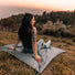 Femme assise sur la couverture Matador Pocket Blanket au coucher du soleil pour détente en pleine nature