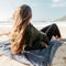 Femme allongée sur la couverture Matador Pocket Blanket au bord de la mer pour confort outdoor