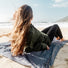 Femme allongée sur la couverture Matador Pocket Blanket au bord de la mer pour confort outdoor