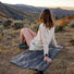 Femme assise sur la mini couverture Matador Pocket Blanket Mini lors d'une sortie vélo en pleine nature