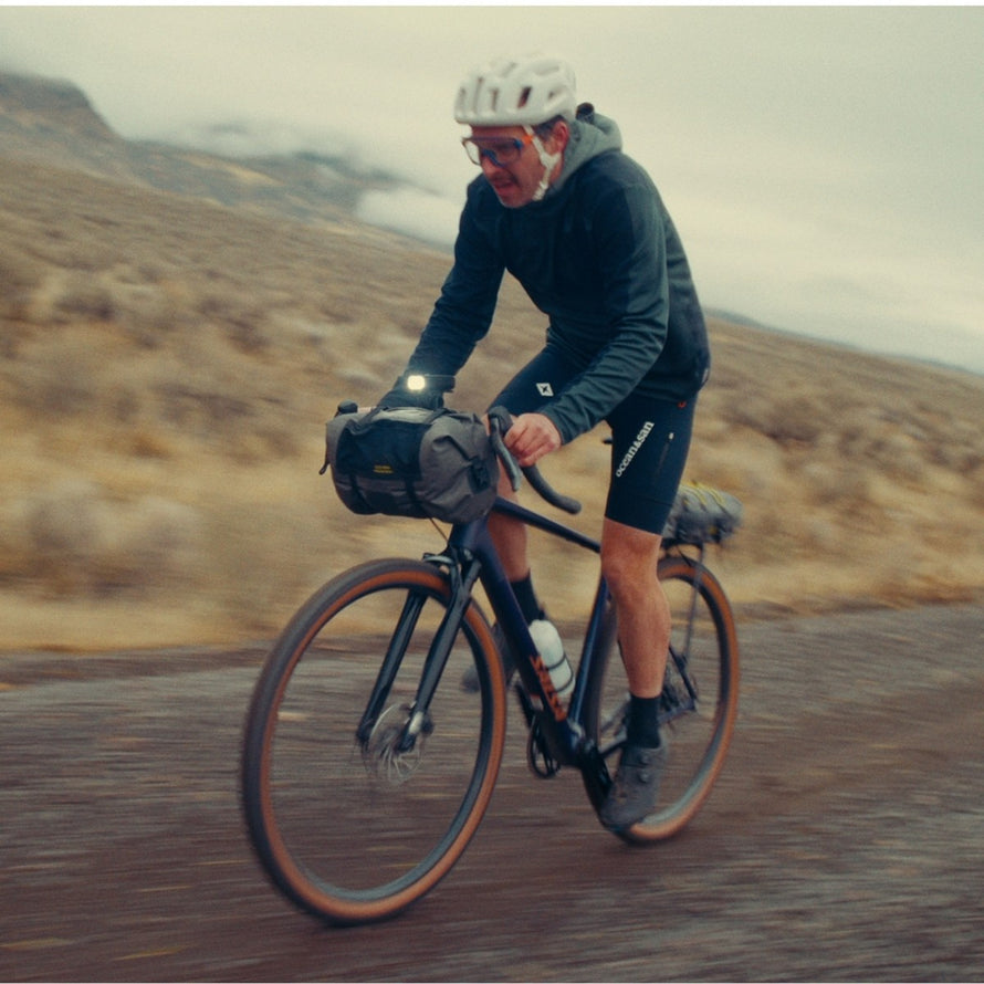 Cycliste équipé d'une sacoche de guidon Old Man Mountain Manzanita cradle sur vélo gravel en pleine aventure