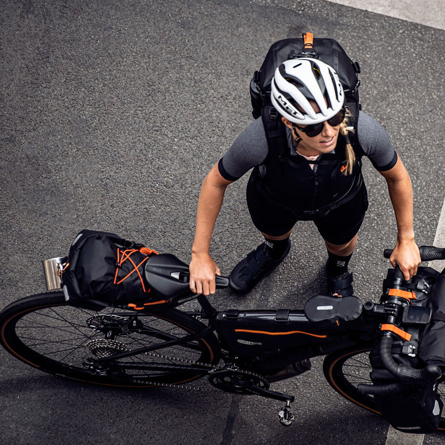Cycliste avec sacoche de selle etanche Ortlieb Seat-Pack 11-16,5L pour bikepacking et aventures sur velo
