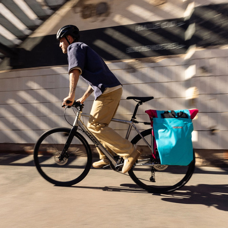Sacoche velo convertible sac a dos Vario Ortlieb bleu et rose fixee a l'arriere du velo en ville