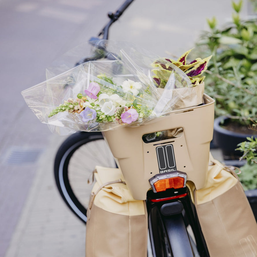 Panier Basil Cento Neo taupe fixé sur vélo avec fleurs, idéal pour balades urbaines et transport sécurisé