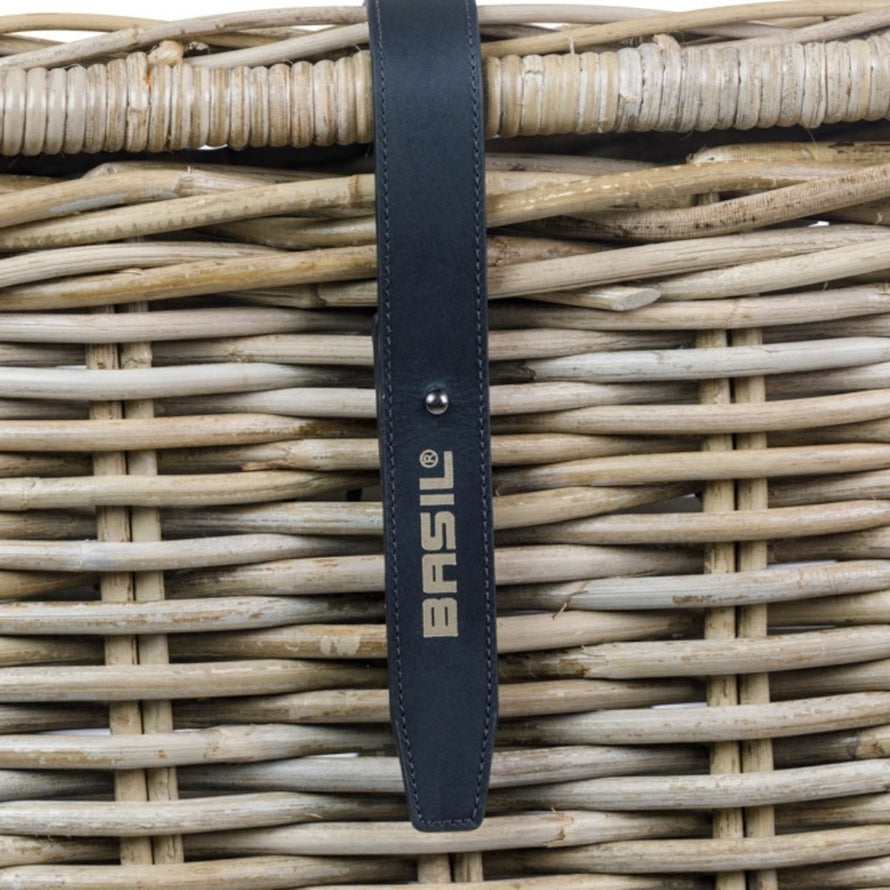 Panier vélo avant Basil Dax avec couvercle en rotin tressé et sangle noire marquée Basil