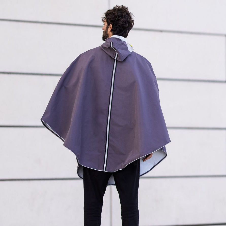 Cape de pluie vélo urbaine unisexe imperméable recyclée avec capuche, portée par un cycliste en ville.