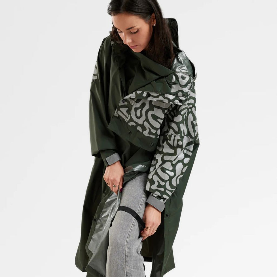 Femme fixantt un poncho de pluie réfléchissant avec capuche pour vélo Romea Urban Circus kaki 