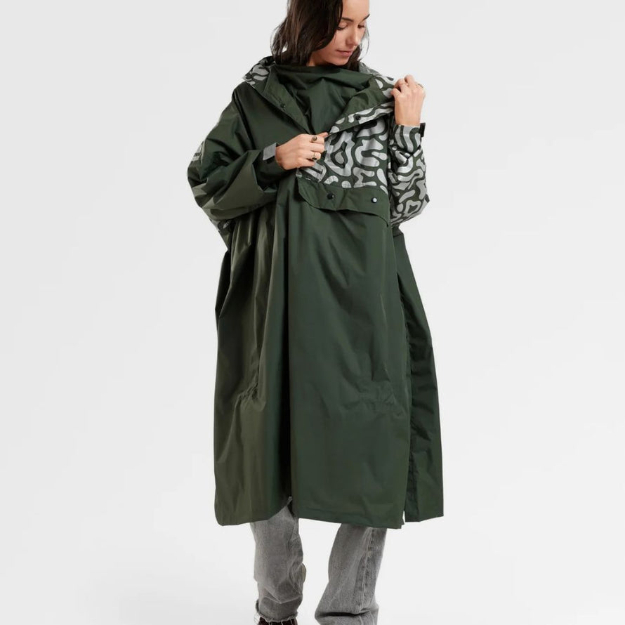 Femme portant un poncho de pluie réfléchissant avec capuche et boutons pressions Romea Urban Circus kaki 