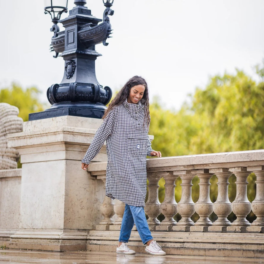Femme souriante en poncho de pluie vélo recyclé Le Temps des Grenouilles motif pied-de-poule en extérieur urbain