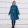 Femme souriante en poncho de pluie vélo recyclé Le Temps des Grenouilles motif pied-de-poule bleu en extérieur