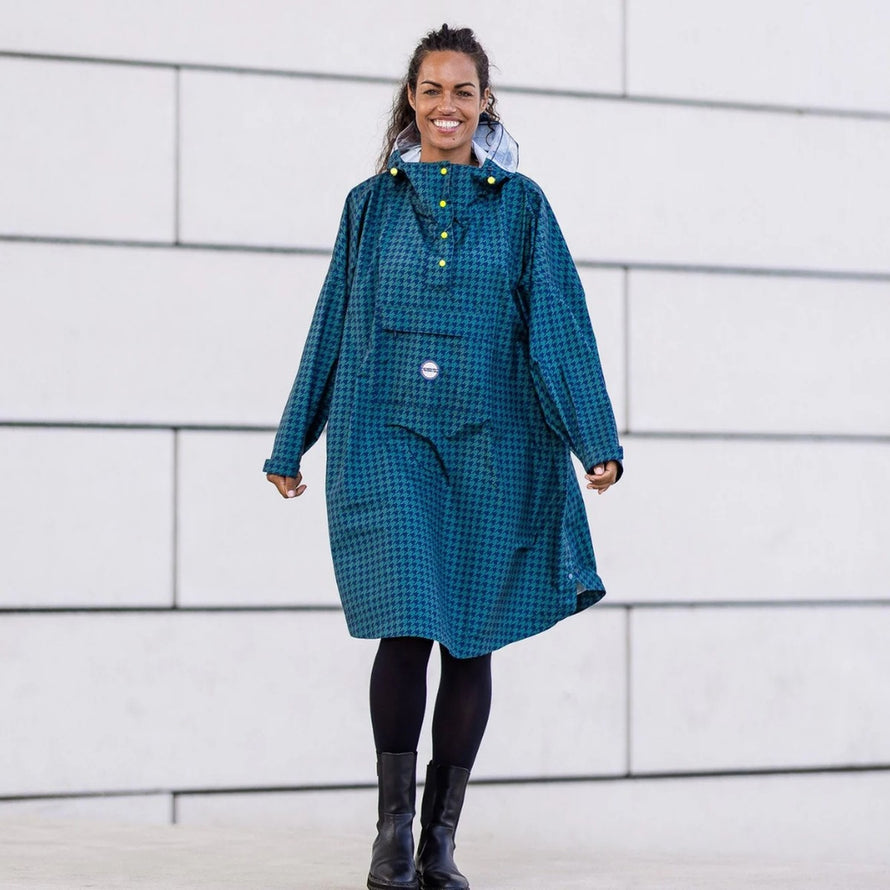 Femme souriante en poncho de pluie vélo recyclé Le Temps des Grenouilles motif pied-de-poule bleu en extérieur