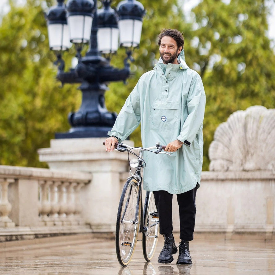 Homme avec poncho de pluie vélo recyclé Le Temps des Grenouilles vert clair, prêt pour balade urbaine sous la pluie