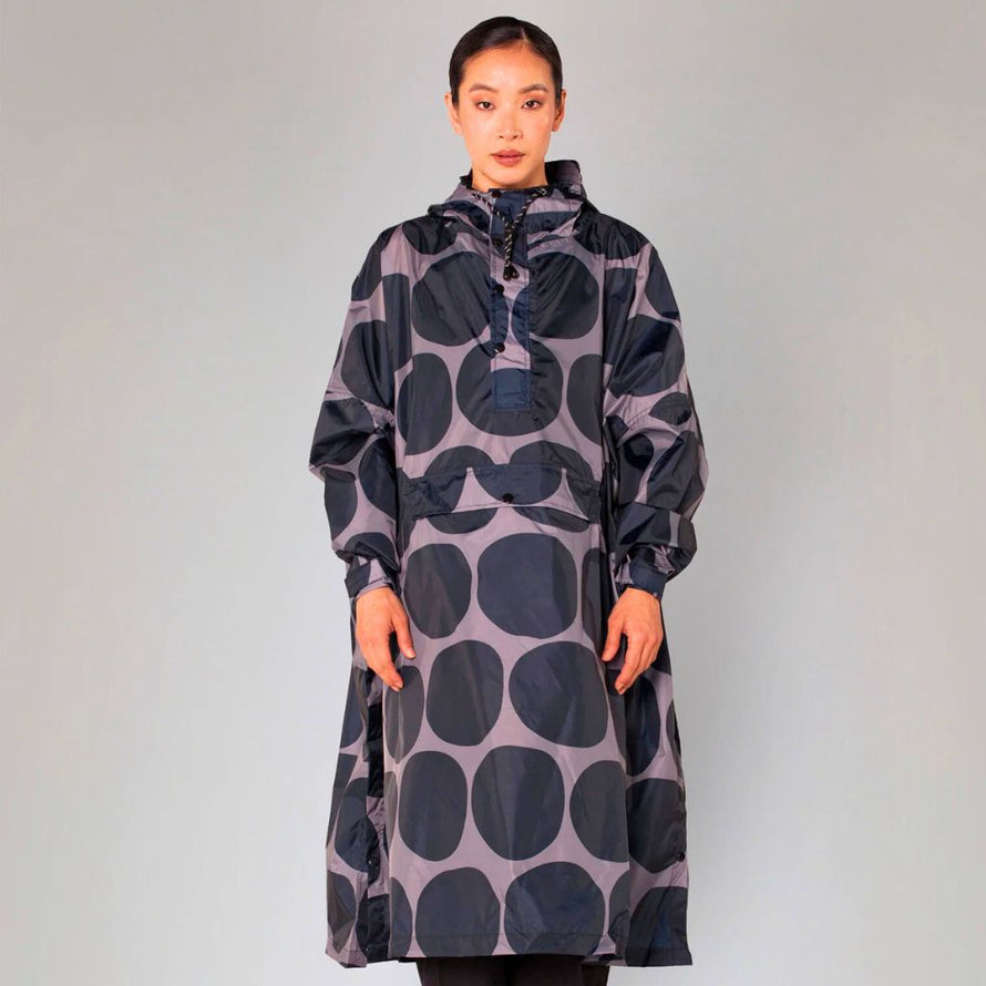 Poncho de pluie Rainkiss Black Polka, imprimé à grands pois noirs sur fond gris, look minimaliste et élégant pour les déplacements urbains sous la pluie.