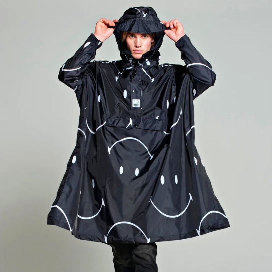 Poncho imperméable Rainkiss Half Moon Smiley, imprimé moderne à grands motifs Smiley, idéal pour un style urbain original et joyeux sous la pluie.