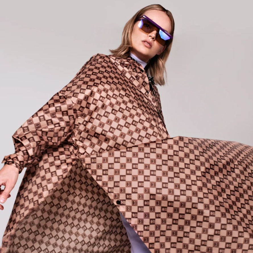 Poncho de pluie Rainkiss Damier, coupe ample et graphique, motif à carreaux marron pour un style élégant et urbain à vélo.