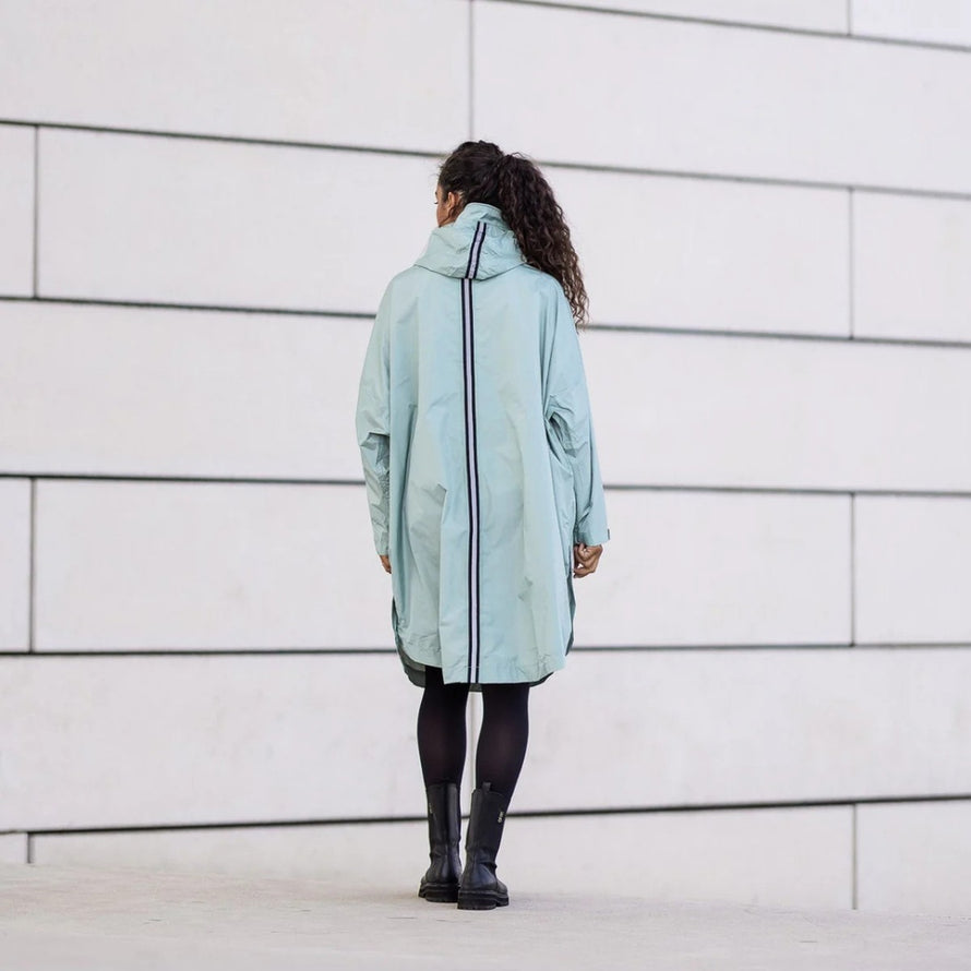 Femme vue de dos portant poncho de pluie vélo recyclé Le Temps des Grenouilles bleu clair urbain