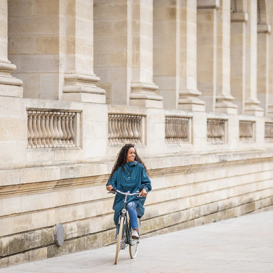 Femme en poncho de pluie vélo recyclé Le Temps des Grenouilles motif pied-de-poule bleu urbain à vélo en ville