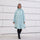 Poncho de pluie vélo recyclé Le Temps des Grenouilles en vert pâle porté par une femme souriante