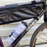 Ce porte-bidon à entrée latérale permet d'emporter un grand bidon d'eau sur un vélo équipé d'une sacoche de cadre sans gêne.