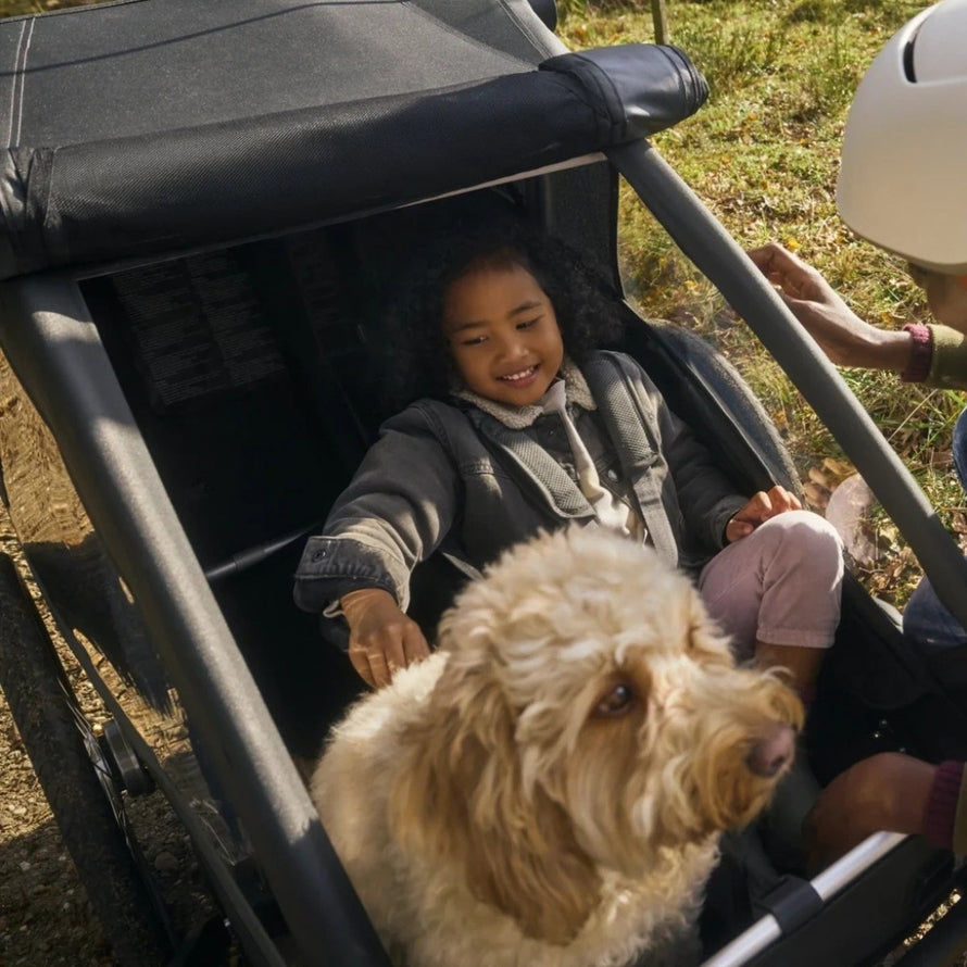 Remorque velo modulaire Yuuna Croozer avec enfant et chien installes confortablement pour balade en plein air
