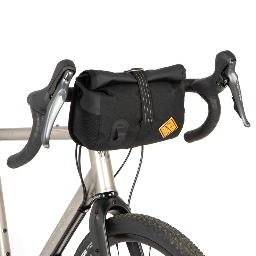 Sacoche guidon 4L Restrap Rolltop Canister en situation de bikepacking vu de profil.