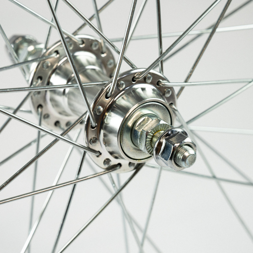 Gros plan sur l’axe boulonné de la roue arrière argentée, montrant le système de serrage et les rayons en acier.
