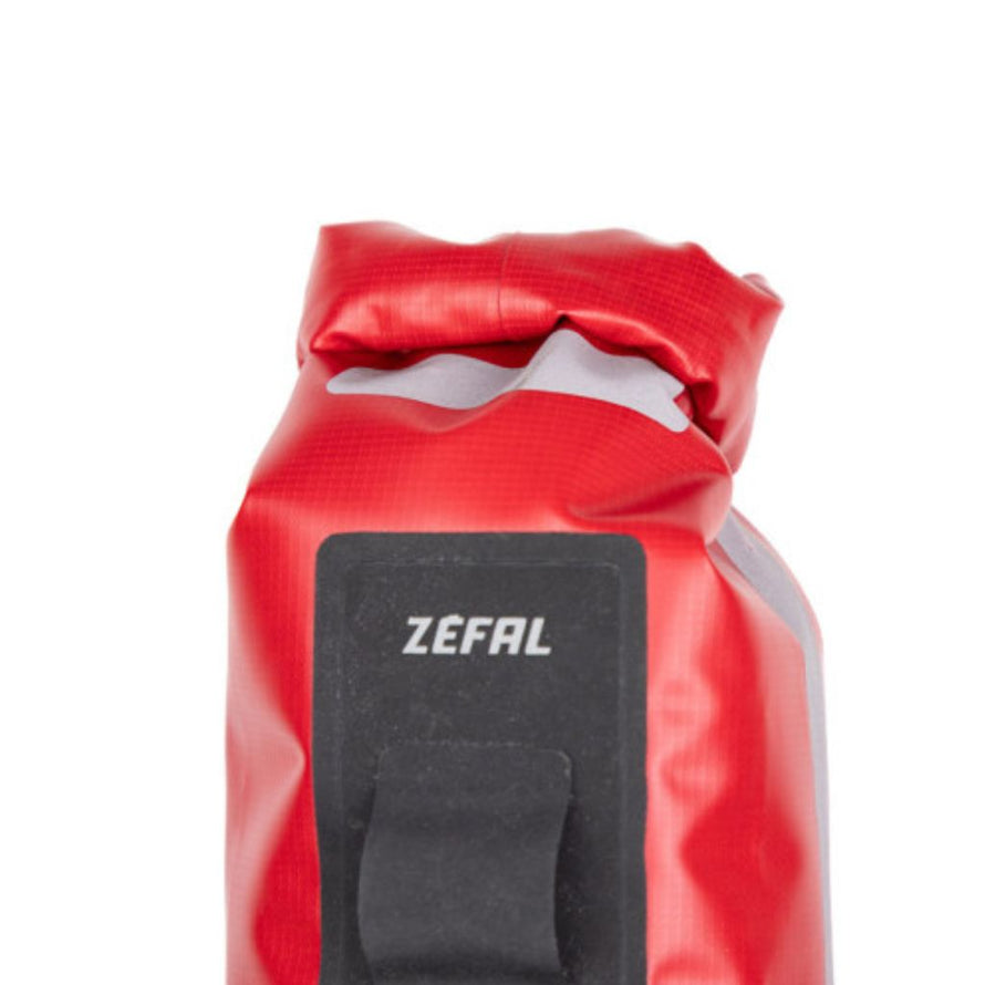Vue rapprochée du sac Zéfal rouge fermé, montrant le patch réfléchissant et le logo