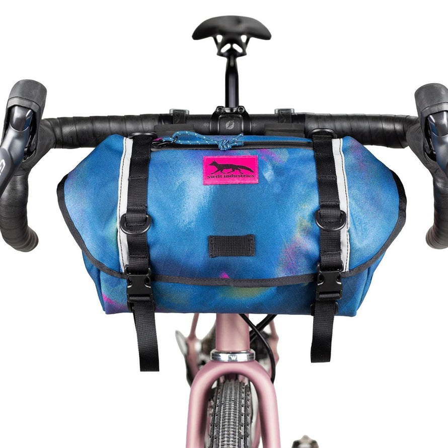 Sacoche de guidon Catalyst Pack Swift Industries bleu avec logo rose fluo, idéale pour bikepacking et cyclotourisme