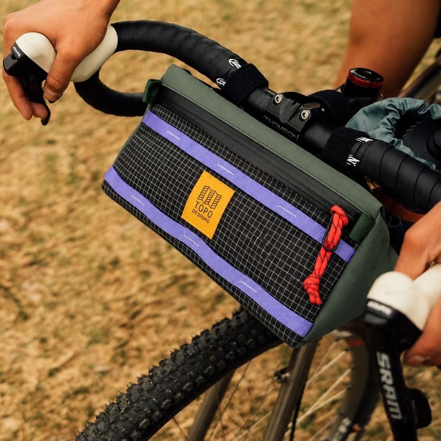 Sacoche de guidon Topo Designs Bike Bag 3L noire avec accents verts, violets et zip rouge, idéale pour cyclistes