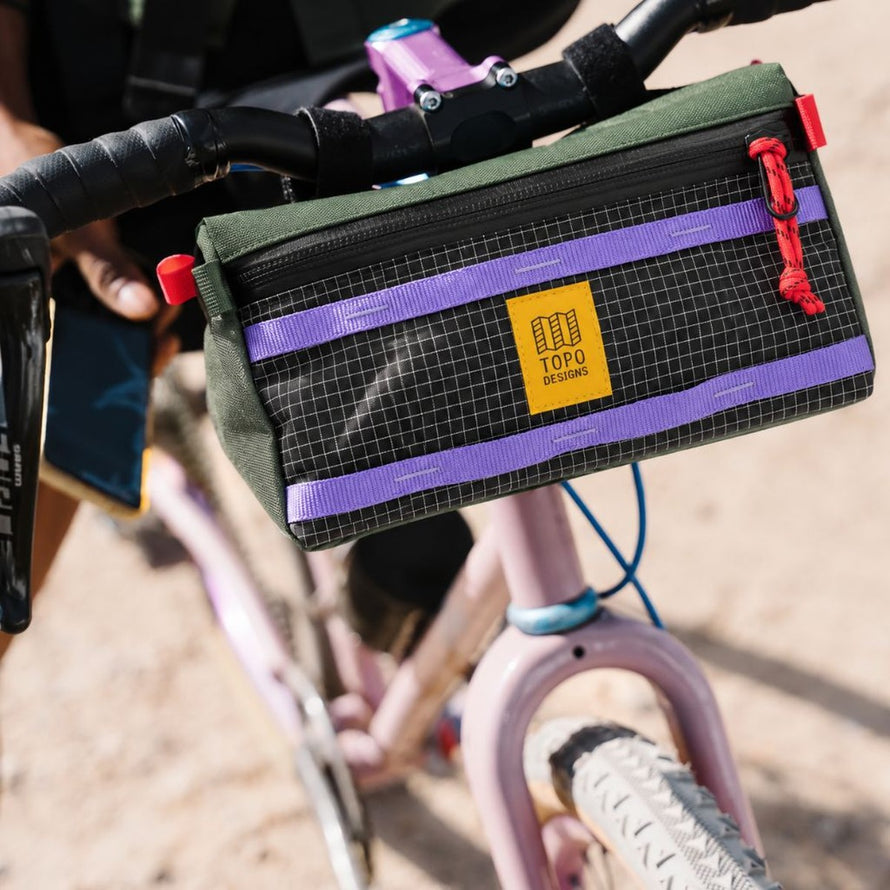 Sacoche de guidon vélo Topo Designs Bike Bag 3L verte avec bandes violettes et zip rouge, robuste et pratique