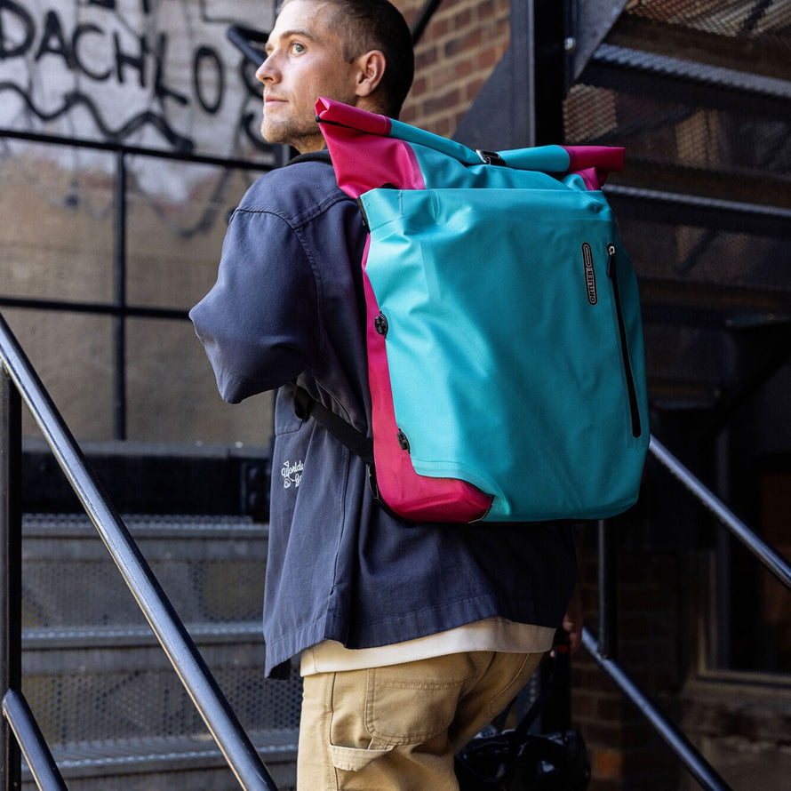 Sacoche vélo convertible sac à dos Vario Ortlieb portée en ville sur escalier couleur bleu et rose