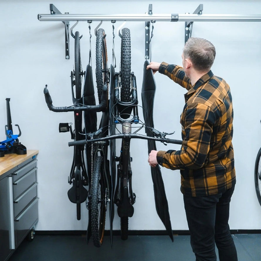 Homme utilisant le tapis de protection vélo Stashed Launch Pad pour protéger plusieurs vélos suspendus