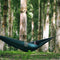 Hamac Ticket to the Moon Original vert fonce suspendu en foret, parfait pour detente et loisirs en plein air
