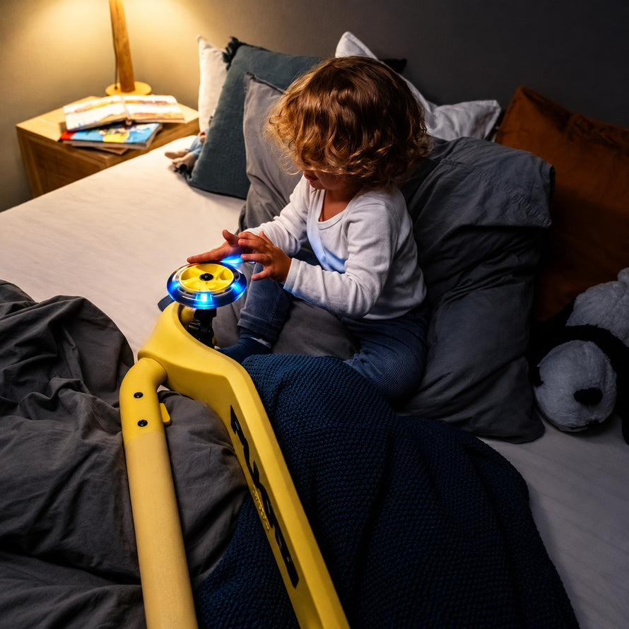 Enfant jouant avec trottinette Puky PUSH 3 roues pliable jaune avec lumières LED, dès 2 ans pour sécurité et plaisir