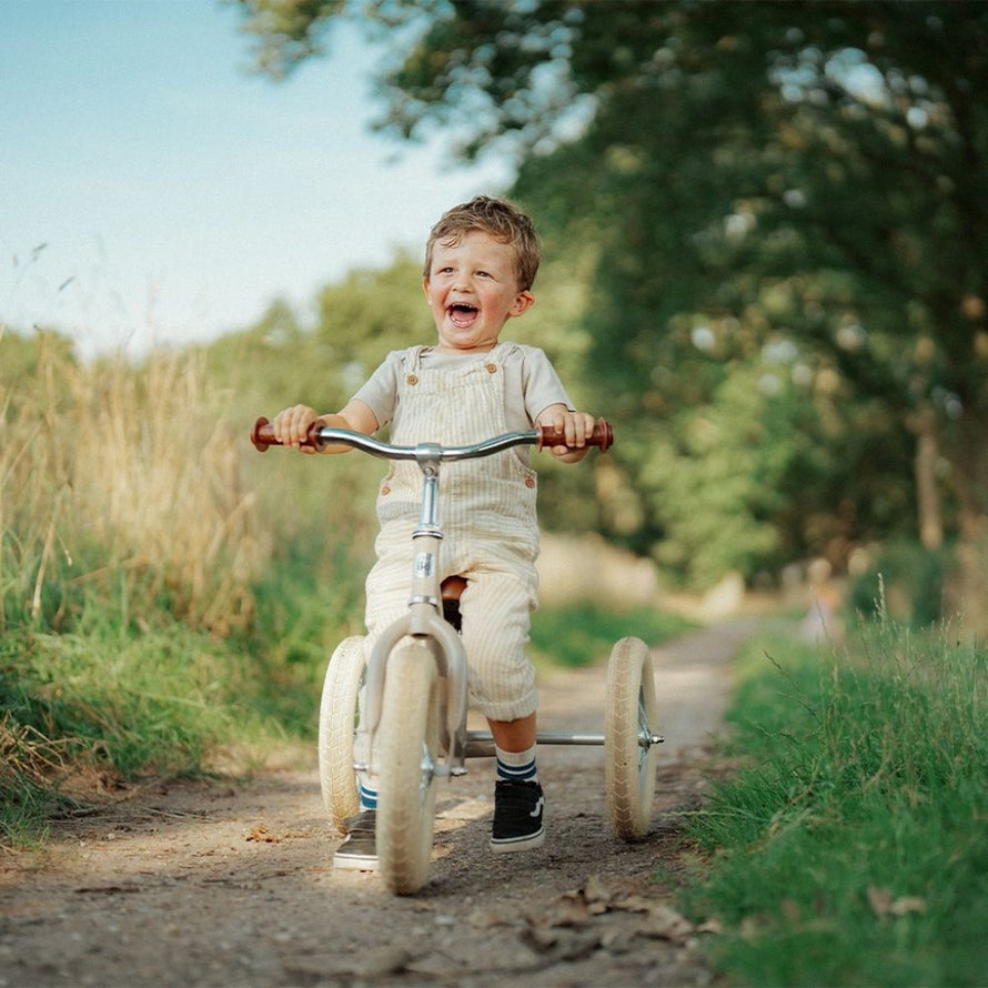 Enfant heureux sur draisienne evolutive 2-en-1 Urban Iki beige convertible en tricycle en pleine nature