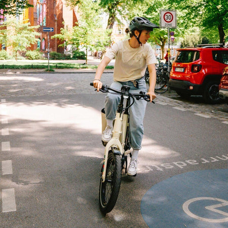 Femme en t-shirt Vaude Cyclist Casual beige à vélo en milieu urbain, style décontracté et écologique