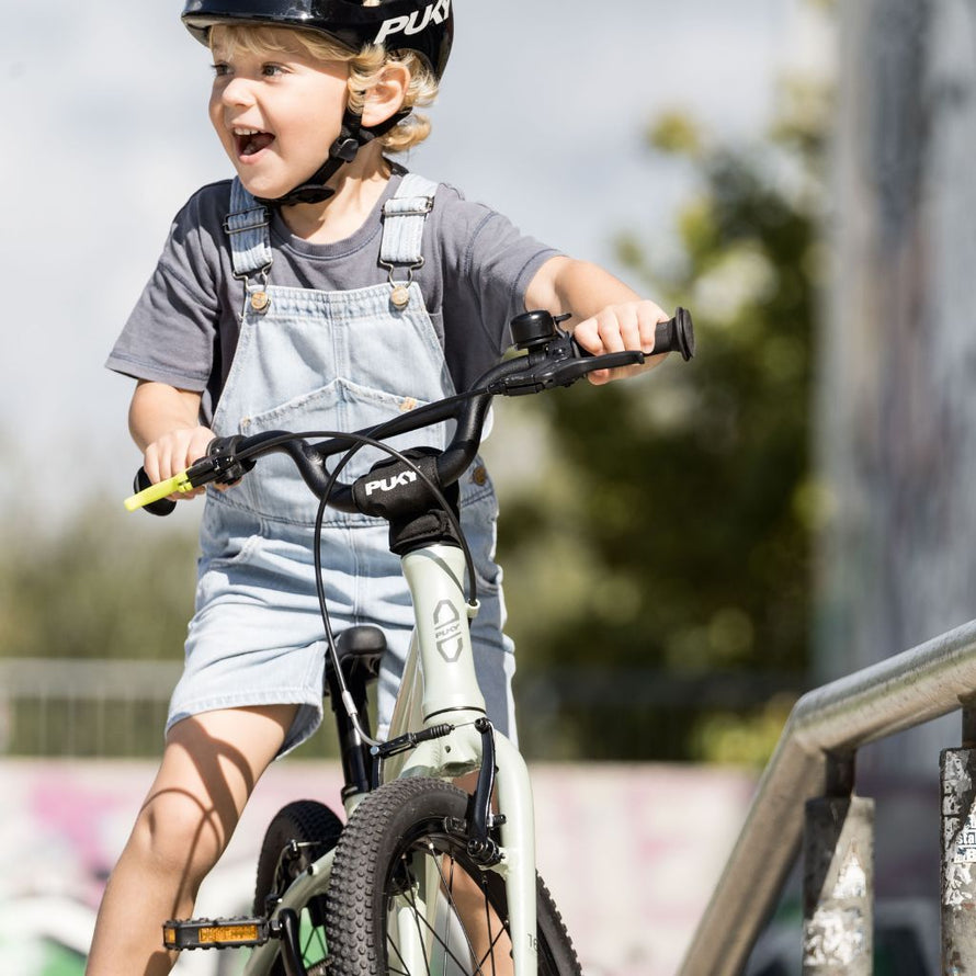 Enfant souriant apprenant à rouler sur le vélo PUKY LS-PRO 14, cadre ergonomique et freins colorés